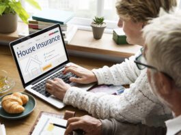 Two people sitting at a table using a laptop to search for home insurance online.