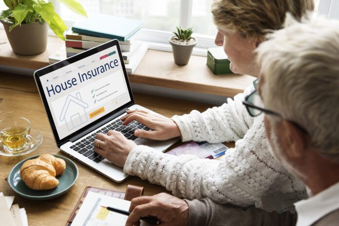 Two people sitting at a table using a laptop to search for home insurance online.