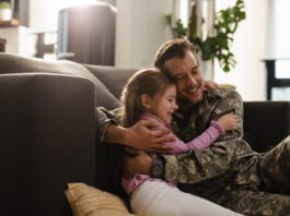 Father hugging his daughter on the sofa, creating a warm, loving moment in a cozy living room.