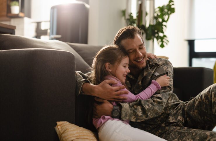 Father hugging his daughter on the sofa, creating a warm, loving moment in a cozy living room.